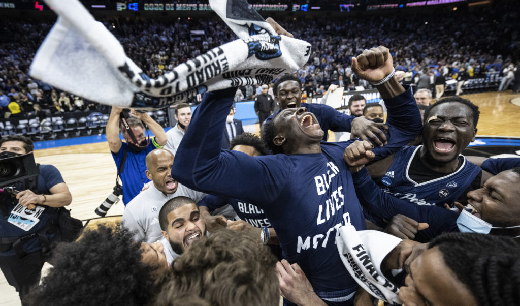 St. Peter's University basketball players waving towels while celebrating a win on the court